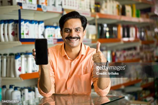 owner showing smart phone at store - indian shopkeeper stock pictures, royalty-free photos & images