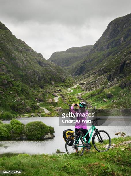 young woman taking photos during a scenic bicycle ride at the gap of dunloe - kerry ireland stock pictures, royalty-free photos & images