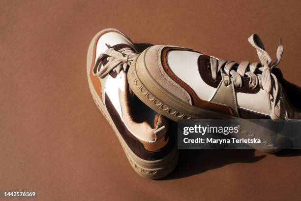 sneakers in brown tones on a brown background. stylish women's shoes. keds. part of a fashionable image. - sapato castanho - fotografias e filmes do acervo