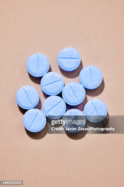 some blue tablets on a brown colored background - pills stock pictures, royalty-free photos & images
