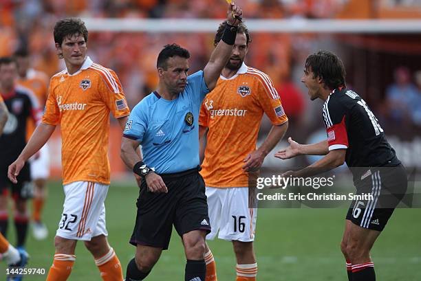 Josh Wolff of D.C. United is given a yellow card penalty by a referee as Bobby Boswell and Adam Moffat of the Houston Dynamo look on during the...