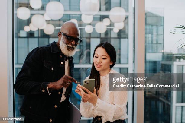 a young woman shows an older man something on her smart phone - enterprise stock pictures, royalty-free photos & images