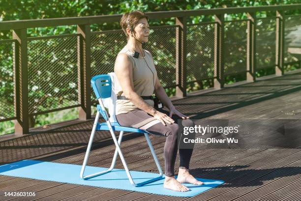 a 70 years old yoga instructor demonstrating yoga asanas on chair - yoga chair stockfoto's en -beelden