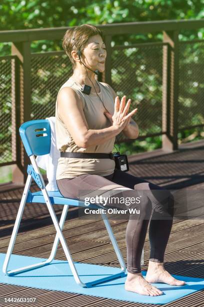 a 70 years old yoga instructor demonstrating yoga asanas on chair - chair exercise stock pictures, royalty-free photos & images