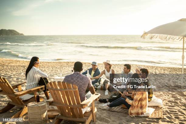 friends having a picnic toasting marshmallows at the beach - bonfire beach stock pictures, royalty-free photos & images