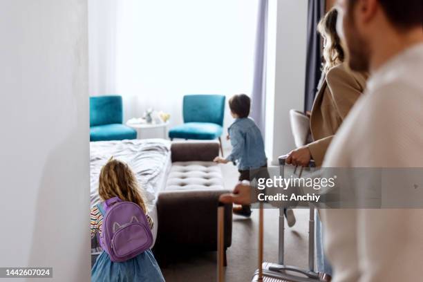 Happy young family with two children entering room at luxury hotel
