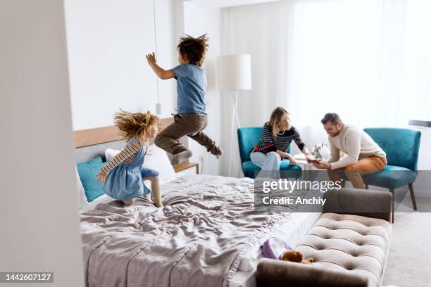 frère et sœur jouant et sautant sur le lit dans la chambre d’hôtel - jump on bed photos et images de collection