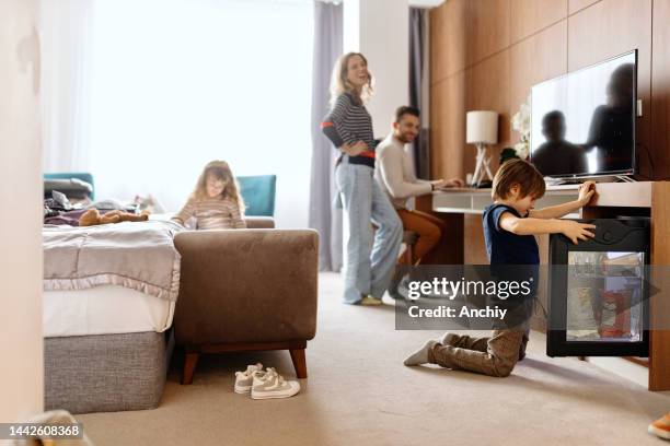 little boy opens the mini bar in the room in search of snacks - mini bar imagens e fotografias de stock