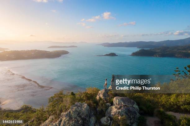 couple enjoying the view on top mountain overlooking whitsundays ocean - australia travel stock pictures, royalty-free photos & images
