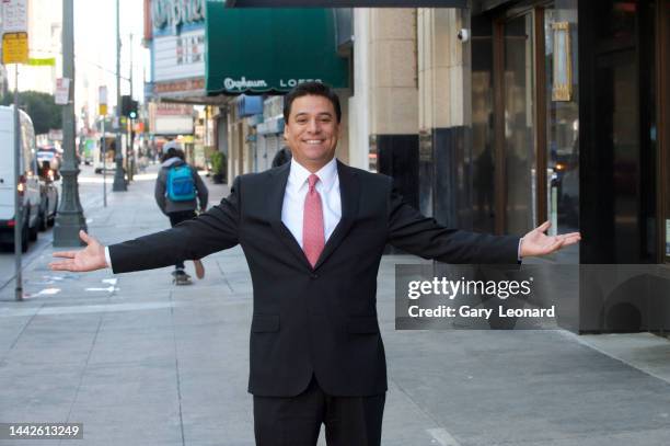On Broadway with the Orpheum Theatre behind him Council Member José Huizar wearing a suit and tie and smiling poses for a portrait with arms...