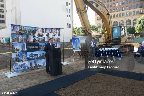 In an empty lot on Olive Street with a bulldozer and ceremonial shovels beside him Council Member José Huizar speaks from the podium to developers at...