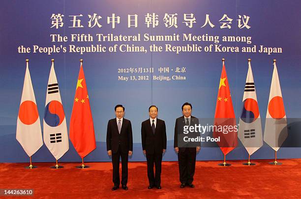 South Korea's President Lee Myung-bak, China Premier Wen Jiabao and Japanese Prime Minister Yoshihiko Noda pose in front of their national flags at...