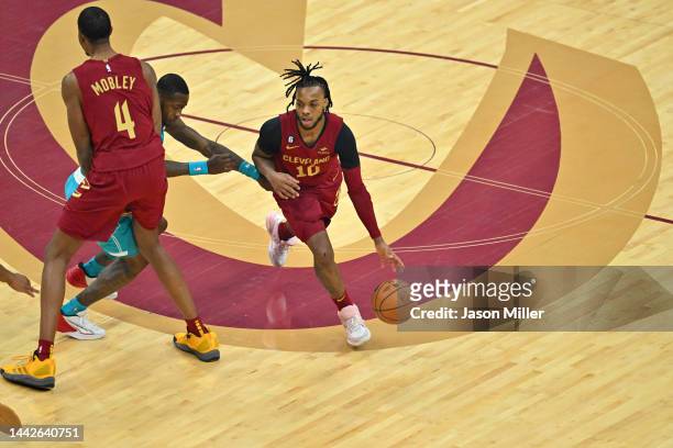 Evan Mobley helps Darius Garland of the Cleveland Cavaliers drive to the basket around Terry Rozier of the Charlotte Hornets during the first quarter...