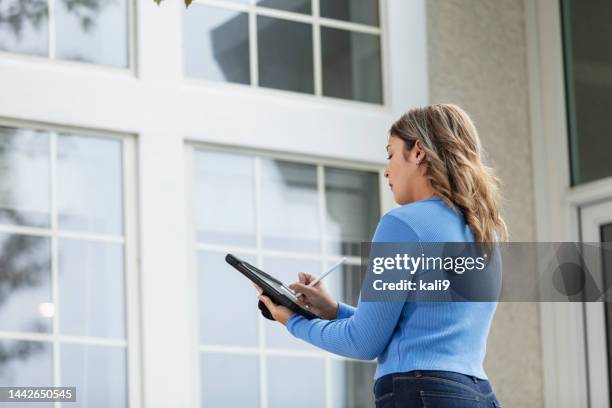 female real estate appraiser using tablet outside house - avaliação imagens e fotografias de stock