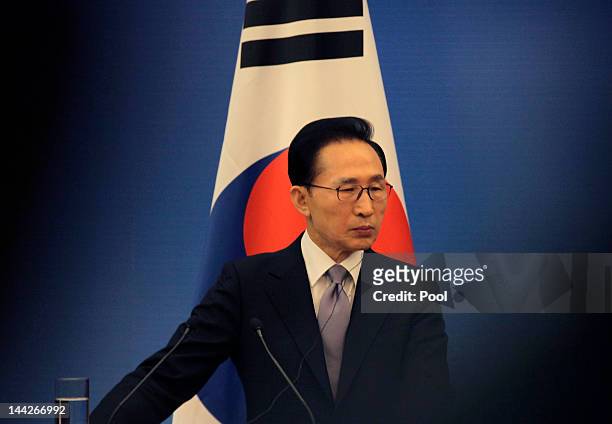 South Korea's President Lee Myung-bak stands in front of a South Korean national flag as he attends a joint news conference of the fifth trilateral...