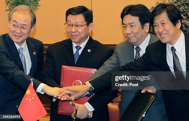 South Korea's Trade Minister Bark Tae-ho , China's Trade Minister Chen Deming and Japan's Trade Minister Yukio Edano hold hands together during a...