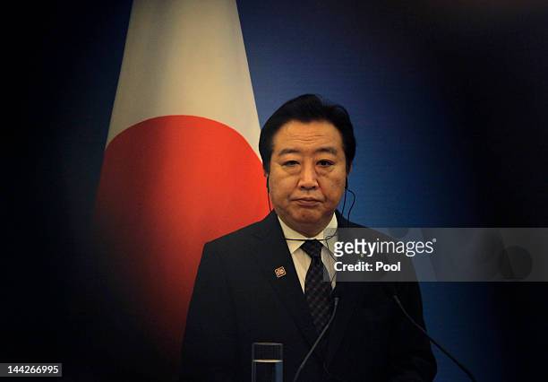 Japan's Prime Minister Yoshihiko Noda stands in front of a Japanese national flag as he attends a joint news conference of the fifth trilateral...