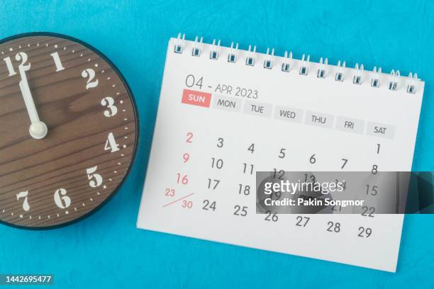 calendar desk 2023: april is the month for the organizer to plan and deadline with a clock against a blue paper background. - april stock pictures, royalty-free photos & images