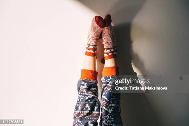 children's feet in christmas socks and pajamas against the backdrop of a sunny wall. the child is having fun. - kids feet in home stock pictures, royalty-free photos & images