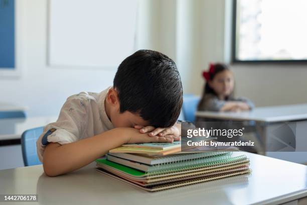 niño durmiendo en su escritorio en un aula - violencia escolar fotografías e imágenes de stock