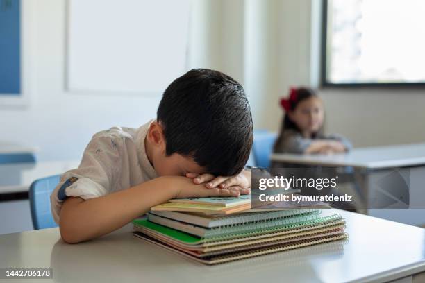 young boy sleeping at her desk in a classroom - adhd child imagens e fotografias de stock