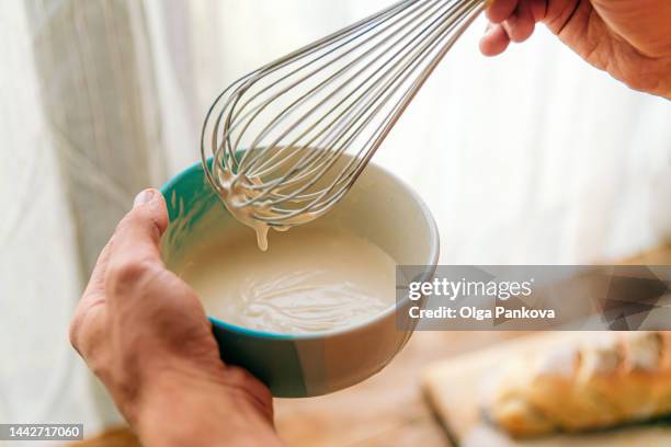 cropped photo of men's hands while cooking white cream sauce with a whisk.  mayonnaise, bechamel - saus stockfoto's en -beelden