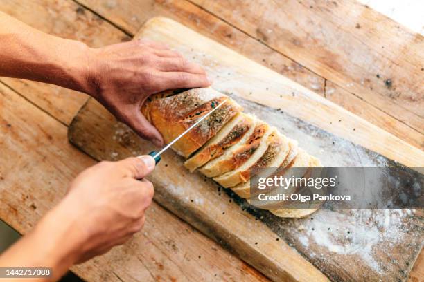 cropped photo of men's hands slicing homemade bread - wholemeal bread stock pictures, royalty-free photos & images