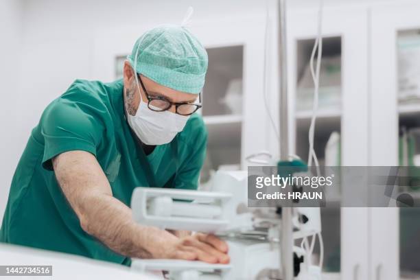 anestesista com bomba de seringa na sala de cirurgia - infused - fotografias e filmes do acervo