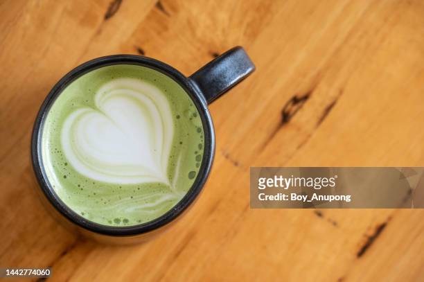 a cup of hot green tea latte on wooden table. - coffee table cafe stock pictures, royalty-free photos & images