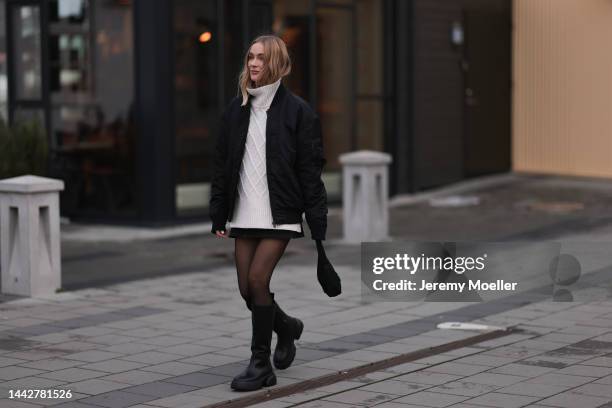 Marie Hindkaer is seen wearing a black Prada nylon bag, black leather Copenhagen Studios CPH145 boots, creme white Samsoe Samsoe knit sweater, Acne...