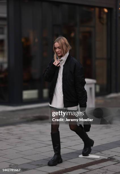 Marie Hindkaer is seen wearing a black Prada nylon bag, black leather Copenhagen Studios CPH145 boots, creme white Samsoe Samsoe knit sweater, Acne...