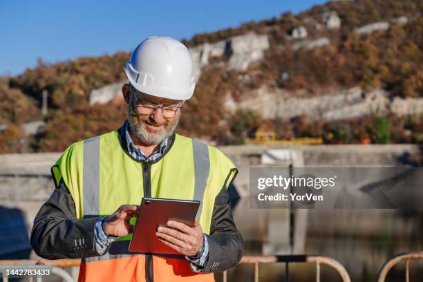 male engineer working with a digital tablet in hydroelectric dam - reservoir engineering stock pictures, royalty-free photos & images