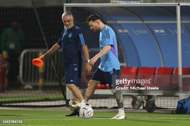 Lionel Messi of Argentina alongside walks alongside medical staff member Javier Martinez as he trains alone from the main squad during the Argentina...