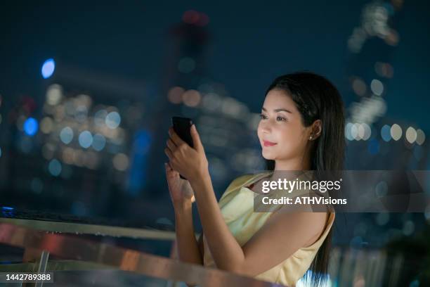 successful businesswoman owner using phone checking an e-mail at the rooftop of luxury hotel at night - see the bigger picture stock pictures, royalty-free photos & images