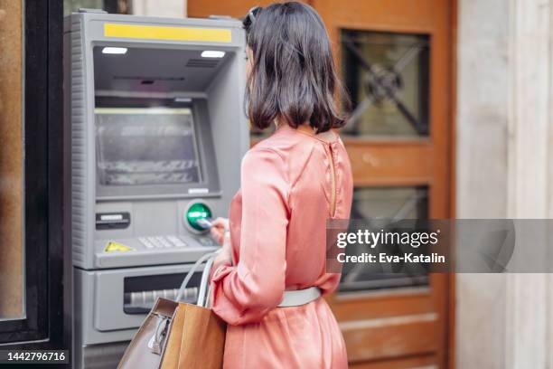 young woman is withdrawing cash from an atm machine - hungary summer stock pictures, royalty-free photos & images