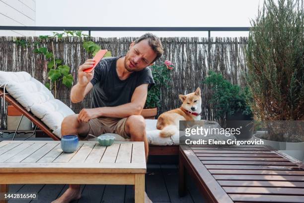 adult single father and his domestic dog resting on roof deck of their condo on a summer day - backyard deck stockfoto's en -beelden
