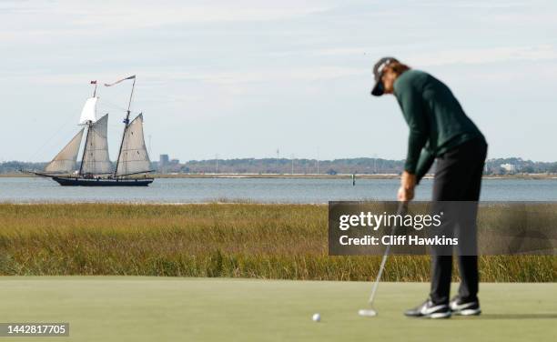 Patrick Rodgers of the United States putts on the 14th green as the Tall Ship Lynx passes behind at Sea Island Resort Seaside Course on November 19,...