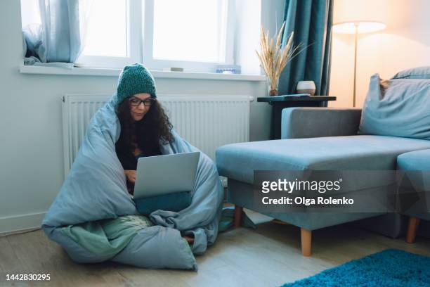 central heating problems, cold temperature. woman feels cold while working at home - froid photos et images de collection