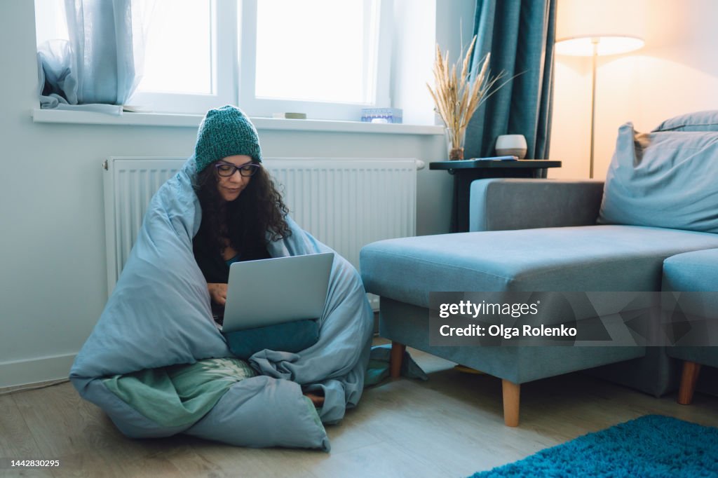 Central heating problems, cold temperature. Woman feels cold while working at home