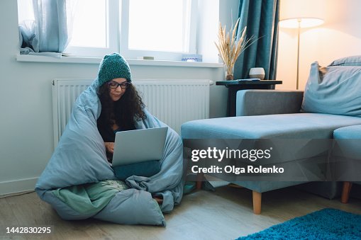 Central heating problems, cold temperature. Woman feels cold while working at home Central heating problems, cold temperature. Woman feels cold while working at home