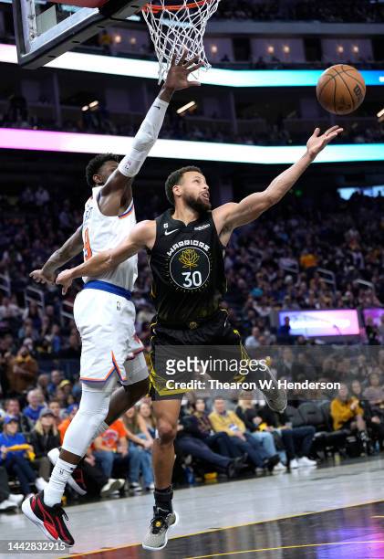 Stephen Curry of the Golden State Warriors goes up to shoot an gets fouled by RJ Barrett of the New York Knicks during the fourth quarter of an NBA...