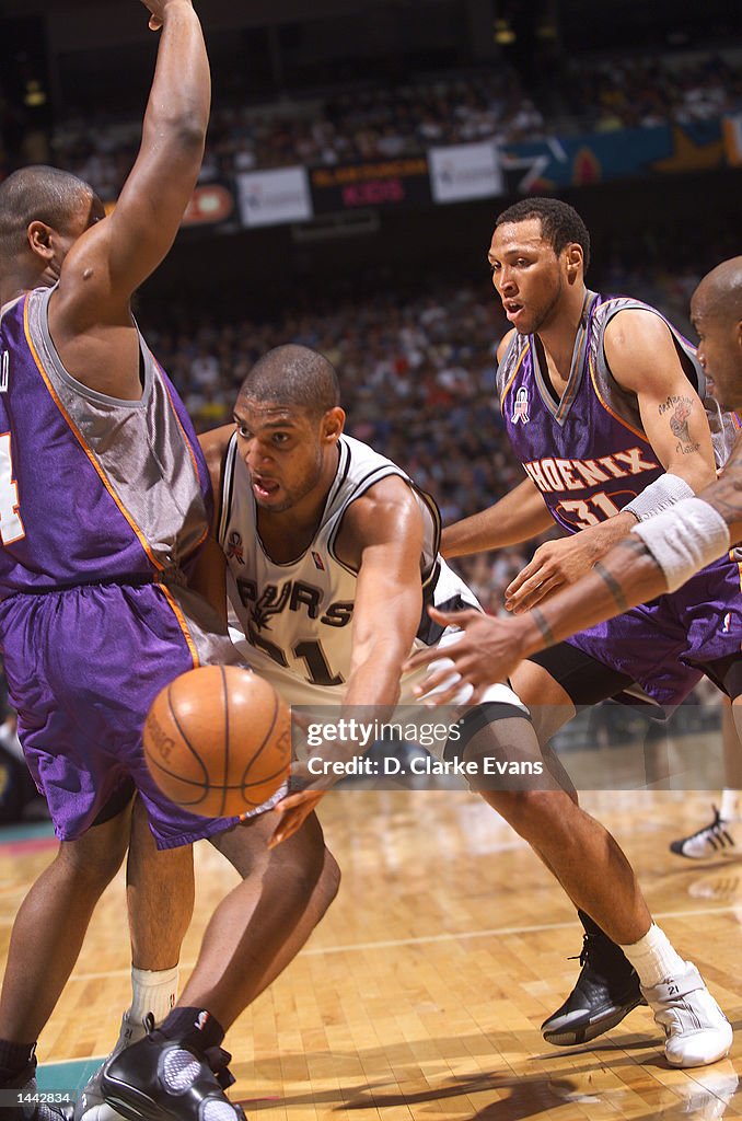 Tim Duncan # 21 of the San Antonio Spurs  finds a space for the past around Alton Ford # 4 of the Phoenix Suns