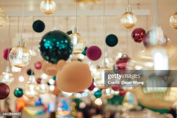 close-up of christmas baubles and christmas lights hanging from the ceiling - christmas decorations in store stock pictures, royalty-free photos & images