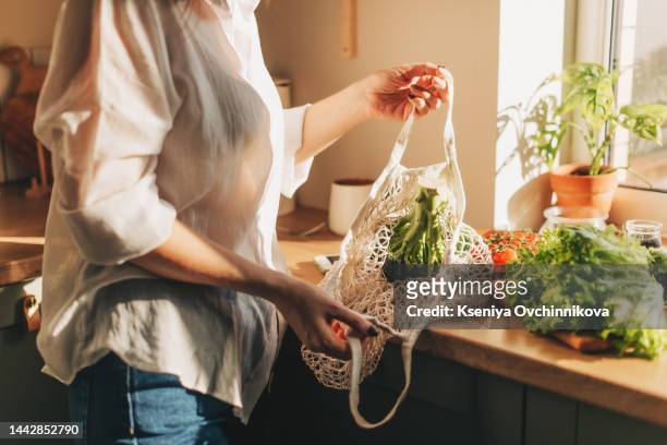 shopping bag with raw vegetables and fruits held by young woman in casualwear - gemüse einkaufen stock-fotos und bilder