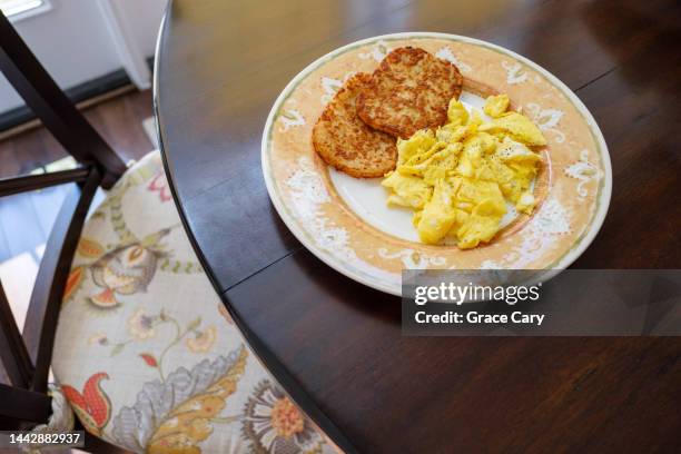 hash brown patties and scrambled eggs on kitchen table - hash brown stock pictures, royalty-free photos & images