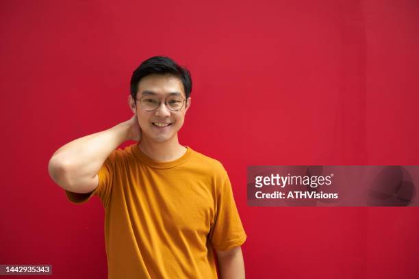 portrait lächelnder vertrauensmann vor rotem hintergrund - showing off stock-fotos und bilder