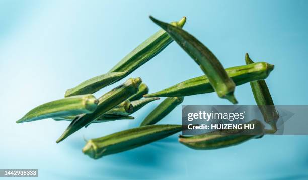 fresh okra flying in air - okra stock-fotos und bilder