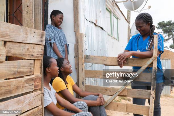 community nurse talking happliy to teenage girls in an informal settlement - africa village stock pictures, royalty-free photos & images