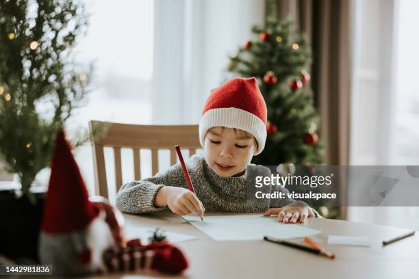 boy writes a letter to santa clause - correspondence imagens e fotografias de stock