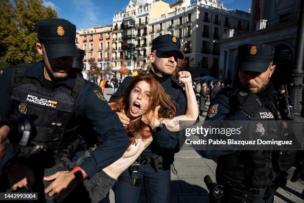Police restrain a FEMEN activist with body paint during a counterprotest before the start of a rally commemorating the 47th anniversary of Spain's...